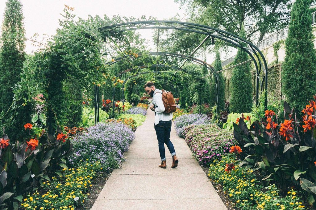 man carrying backpack walking on garden path