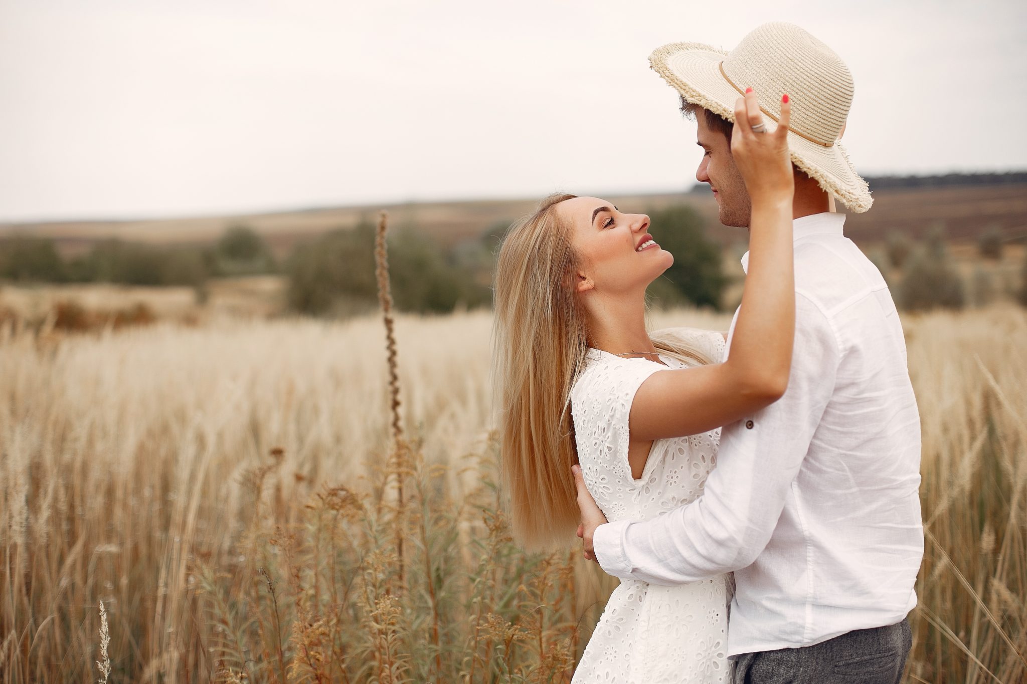 Cute couple in a field. Lady in a white dress. Guy in a white shirt