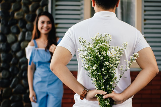 man-holding-baby-s-breath-flower-in-front-of-woman-standing-935789