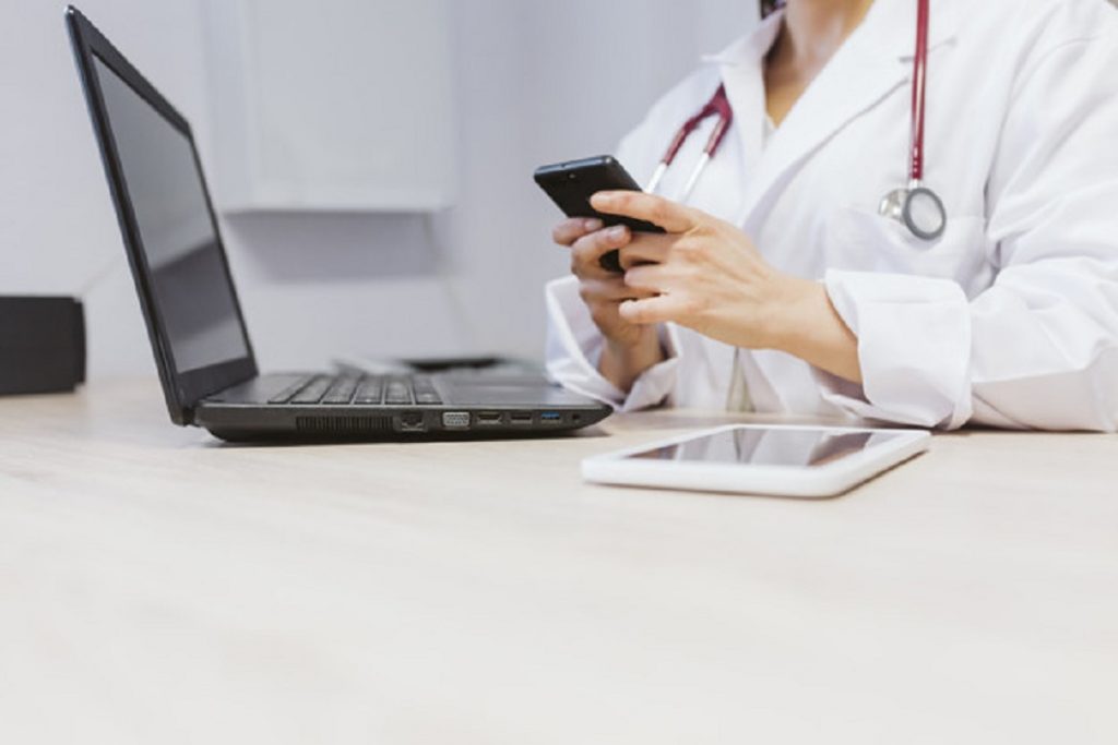 young doctor woman working on laptop at the consult. Using mobil