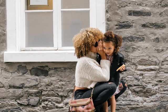 woman wearing white sweater whispering to a daughter